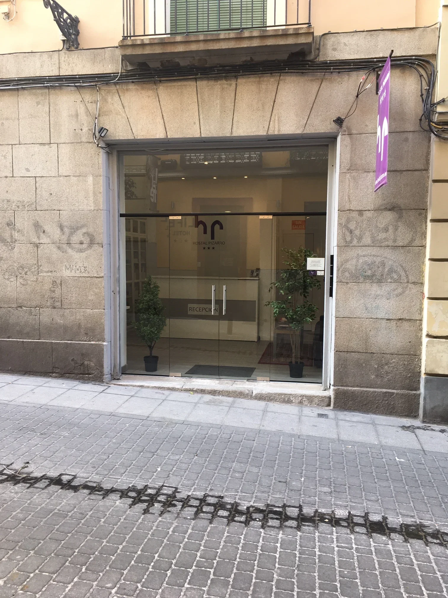 Glass-front entrance to Hostal Pizarro in historic stone building