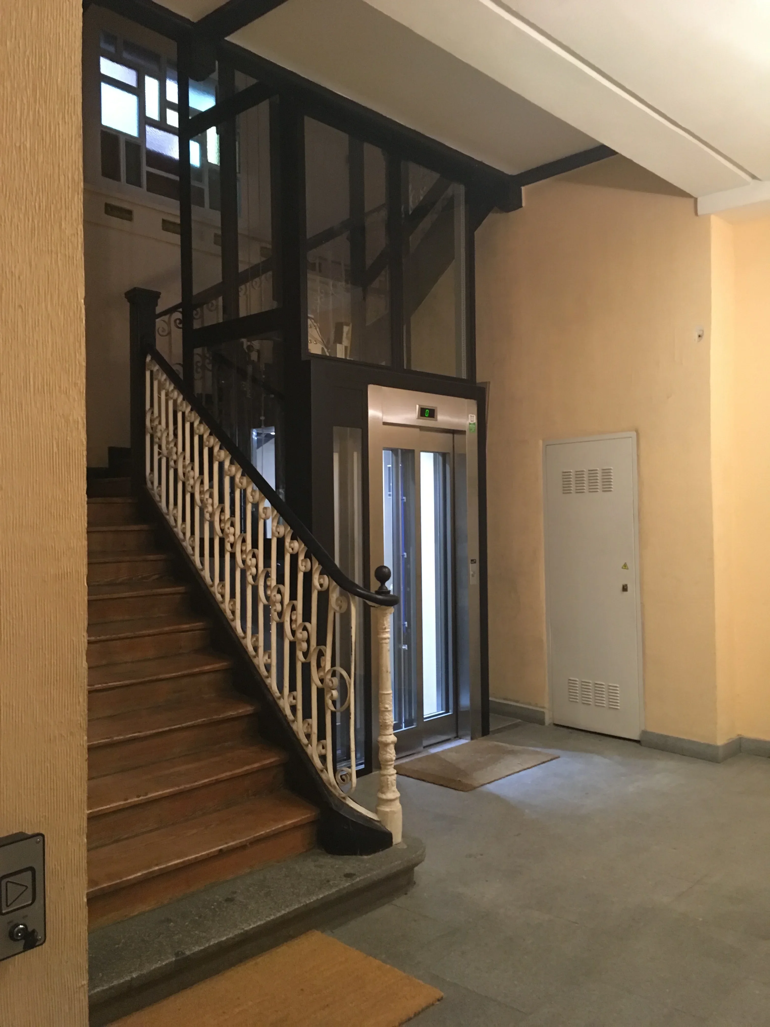 Building lobby with glass elevator shaft in classic staircase