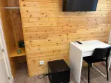 Zona de estar de la habitación con armario, caja fuerte, minibar negro y escritorio blanco